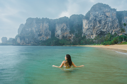 Young Caucasian woman swimming in the sea under the tropical rain