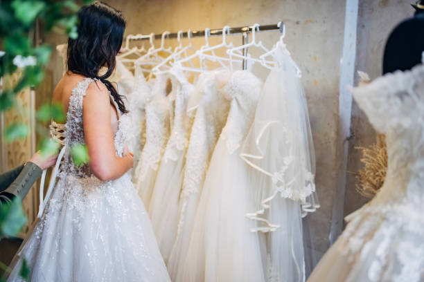 la mariée essaie l’habillage de mariage dans la boutique de mariage - wedding bride buying caucasian photos et images de collection