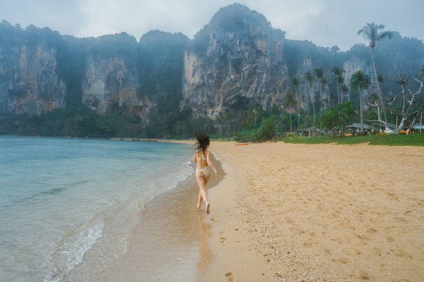 istock Cheerful woman running on the beach  under the rain 1481656691