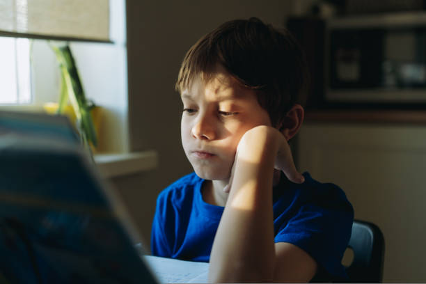 istock caucasian boy doing homework at home iat the table by the window. Image with selective focus 1481663057