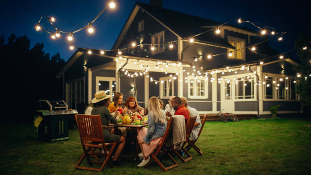 istock Group of Multiethnic Diverse People Having Fun, Communicating with Each Other and Eating at Outdoors Dinner. Family and Friends Gathered Outside Their Home on a Warm Summer Evening. 1481663071
