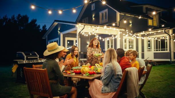 istock Group of Multiethnic Diverse People Having Fun, Communicating with Each Other and Eating at Outdoors Dinner. Family and Friends Gathered Outside Their Home on a Warm Summer Evening. 1481663259
