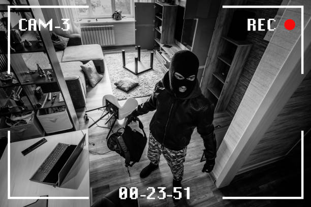 A man in a black mask is trying to rob a house. There is recording on an outdoor video surveillance camera. Robbery of a private house. Criminal concept. black and white camera recording effect A man in a black mask is trying to rob a house. simulation of recording from a surveillance video camera. Robbery of a private house. Criminal concept, apartment theft. black and white camera recording effect intercepting stock pictures, royalty-free photos & images