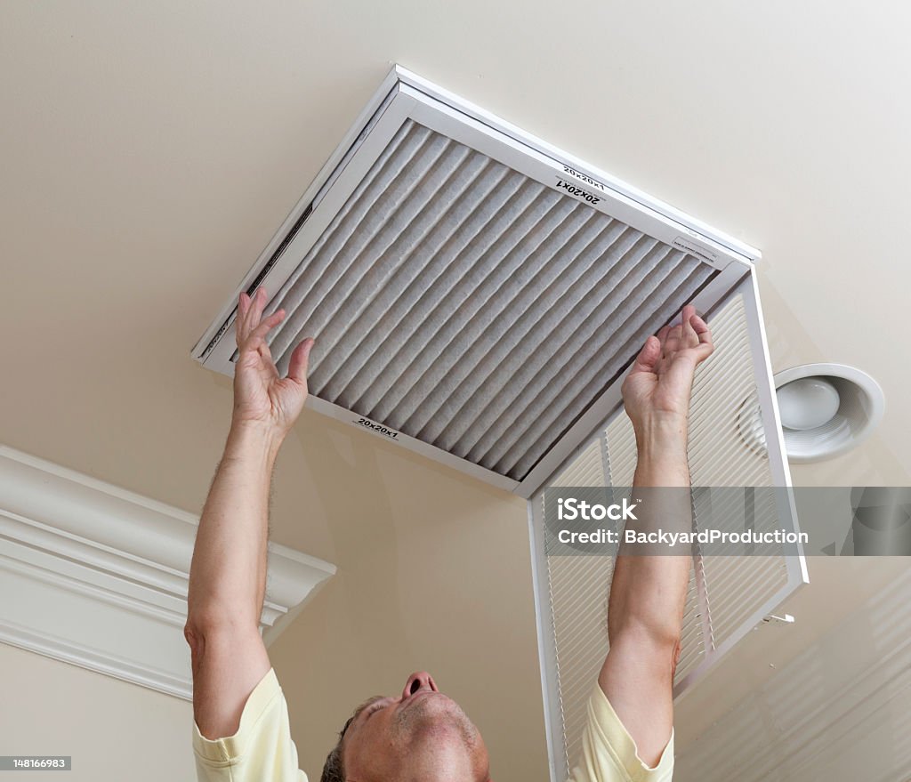 A senior man checking the air conditioner filter Senior male reaching up to open filter holder for air conditioning filter in ceiling Air Purifier Stock Photo
