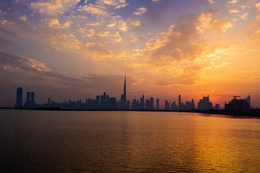 Dubai skyline during sunset. Dubai's skyline sets the scene for a breathtaking sunset, painting the sky with vibrant hues of orange, pink, and gold.