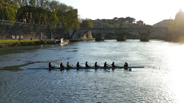 Sportsmen paddle a canoe on the Tiber River in the center of Rome.
