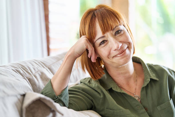 istock Woman smiling while relaxing on her living room sofa 1481684211