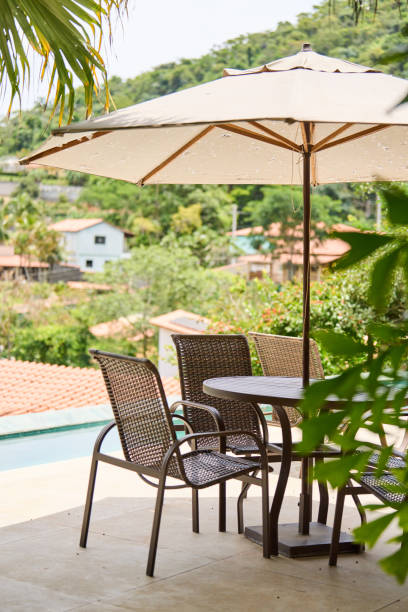 istock Patio table and chairs with an umbrella sitting by a pool in summer 1481684585