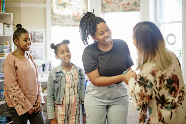 Parent, teacher and kids meeting in classroom at Montessori  school for education, learning and teaching. Child development, mother and educator handshake, conversation and young students in class. stock photo