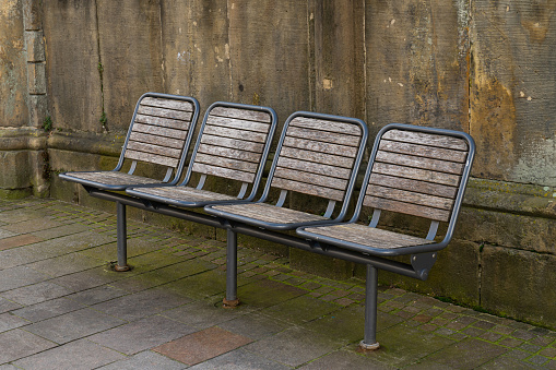 A row of metal-framed wooden benches against a gray concrete wall.