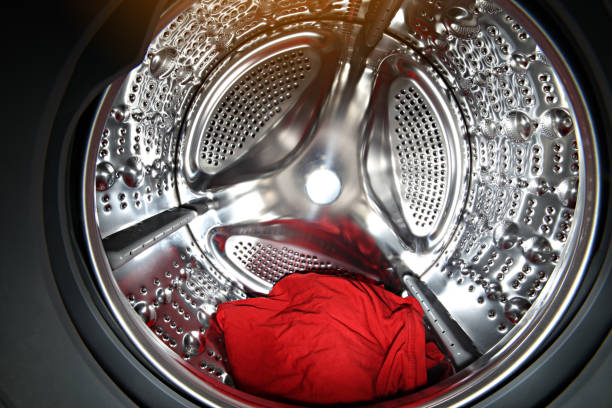 View of the tumble dryer or washing machine drum with red clothes inside. Laundry day. Daily household chores. Domestic and Household Appliance. Home Innovation. View of the tumble dryer or washing machine drum with red clothes inside. Laundry day. Daily household chores. Domestic and Household Appliance. Home Innovation tumble dryer stock pictures, royalty-free photos & images