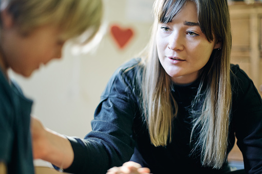 Therapy, mental health and therapist talking to a child on autism or adhd with comfort in clinic. Psychology, healthcare and female kid psychologist speaking to young boy in office at wellness center