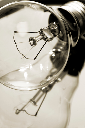 Old-fashioned light bulb reflected, close-up view, light sepia tone .