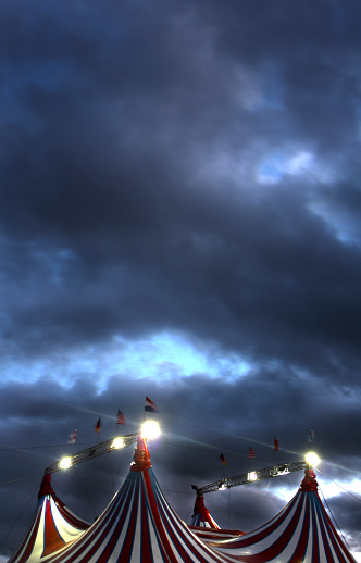 Striped circus red big top with waving flags , Lugo city, Galicia, Spain. Dramatic sunset sky, cloudscape background.