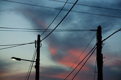 Street light, poles and cables silhouetted,  dusk background.