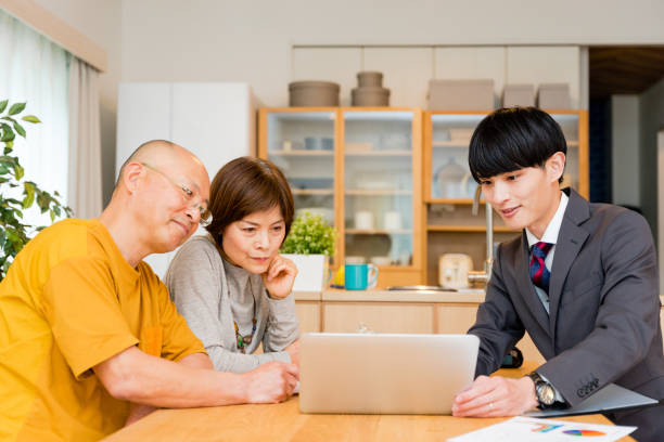 自宅の居間でスーツ姿の若い男性と話す老夫婦 - male nurse 写真 ストックフォトと画像