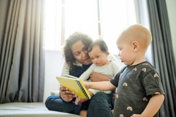 istock Mother, babies and learning with book in home, storytelling and education in house. Development, care and happy mama reading with children, kids or toddlers while bonding and having fun together. 1481696917