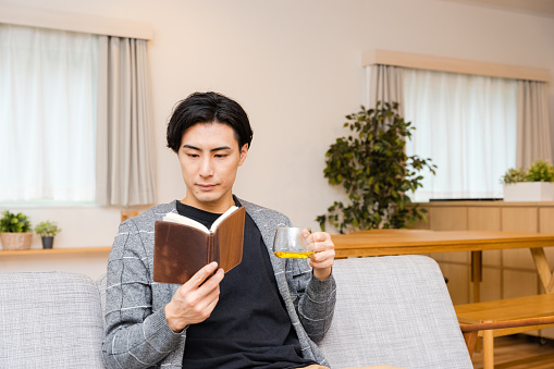 A man in his thirties who enjoys reading a hobby on holidays in his living room