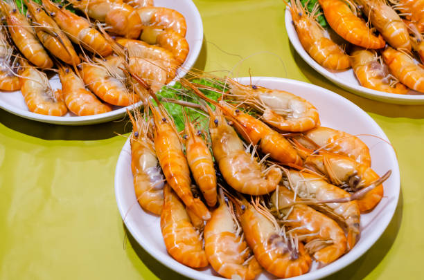 Boiled shrimp ready to eat at the night market in Thailand, grilled shrimp with green lettuce leaves close-up