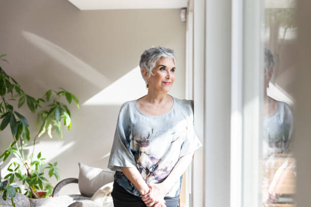 istock Senior woman daydreams while looking out sunroom windows 1481698348