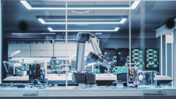 Industrial Programmable Robotic Arm in a Factory Development Workshop. Robot Arm Holding a Prototype Microchip. Tech Facility with Machines, Computers and Research Equipment. Photo Without People. Industrial Programmable Robotic Arm in a Factory Development Workshop. Robot Arm Holding a Prototype Microchip. Tech Facility with Machines, Computers and Research Equipment. Photo Without People. robotic arm lab stock pictures, royalty-free photos & images