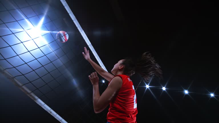 SLO MO Female volleyball player in red jersey hitting the ball across the net