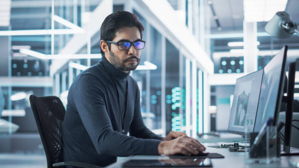 istock Portrait of a Handsome Hispanic Industrial Engineer Developing 3D Model of a Circuit Motherboard on Computer CAD Software in a Factory. Modern Technological Research and Development Center. 1481702614