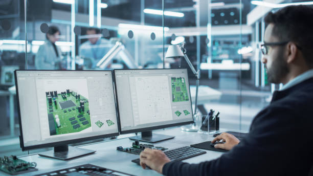 istock Portrait of a Handsome Hispanic Industrial Engineer Developing 3D Model of a Circuit Motherboard on Computer CAD Software in a Factory. Modern Technological Research and Development Center. 1481702720