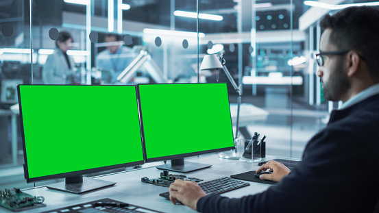 Software Developer Working On A Desktop Computer With Two Green Screen ...
