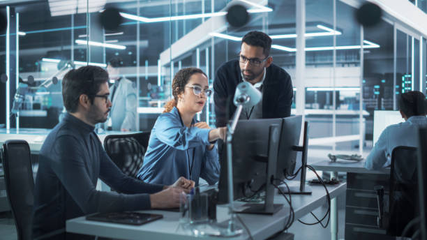 istock Team of Innovative Industrial Engineers Use Computer to Discuss a Technological Project in Industry 4.0 Modern Factory Office. Group of Scientists Work in Research and Development Center. 1481703422