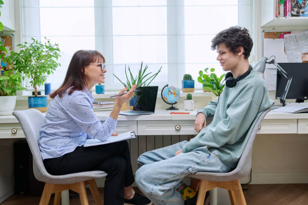 Positive friendly female psychologist talking to young guy stock photo