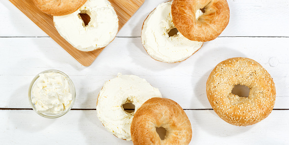 Bagel sandwich with fresh cream cheese for breakfast from above on a wooden board panorama