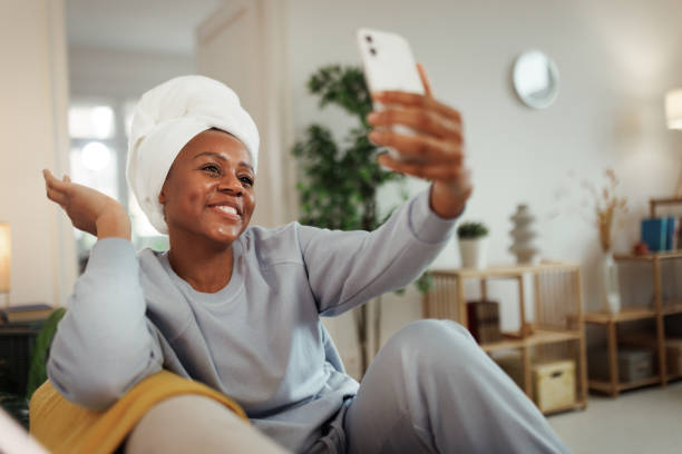 istock Young woman with towel on head relaxing at home, taking a selfie 1481709821