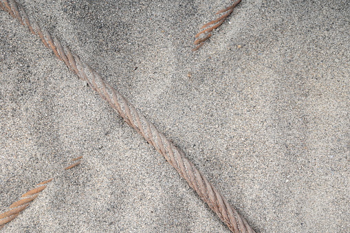 Light sand partially covers two overlapping ropes by the South Thompson River in Kamloops, British Columbia. Spring morning under overcast skies in the Thompson-Nicola Regional District.