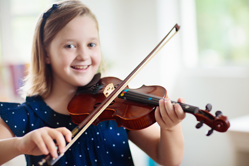 Young female violinist playing her violin on white background.