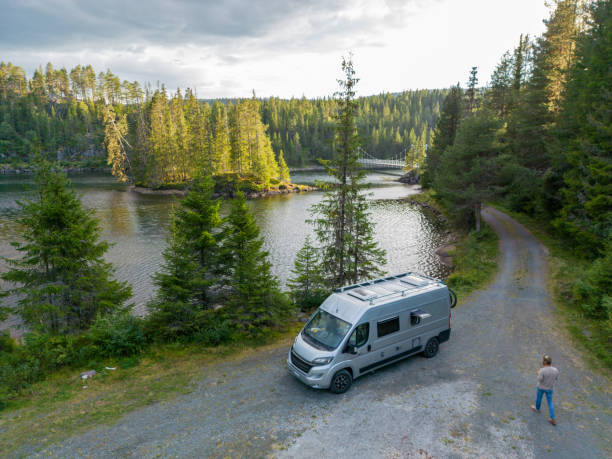 Man walks towards his van parked by the lake, drone view stock photo