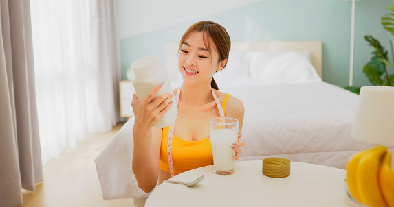 asian woman is drinking natural fruit or vegetable enzyme powder which in water - measure tape on neck