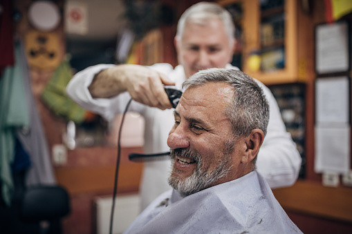 A senior man is getting his hair cut in a barbershop