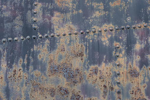 Scratched, stained, rusty sheet metal plate with rivets background texture