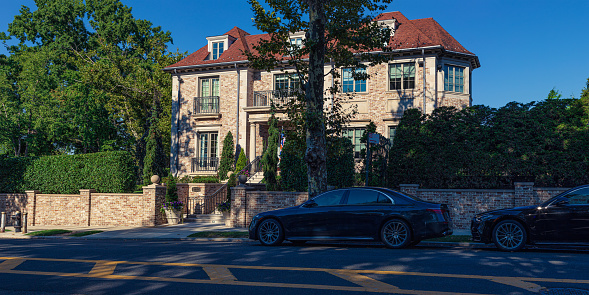 Mansion with Brick Exterior and Red Tile Roof on the corner of Narrows Ave. and 82nd Street in Bay Ridge Neighborhood of Brooklyn, New York, USA. Two Mercedes-Benz S550 Luxury Cars parked on the street in front of the house. Canon EOS 6D (full Frame Sensor) Camera. Canon EF 50mm F/1.8 II Lens. High resolution stitched panoramic image.  2:1 Image Aspect Ratio.