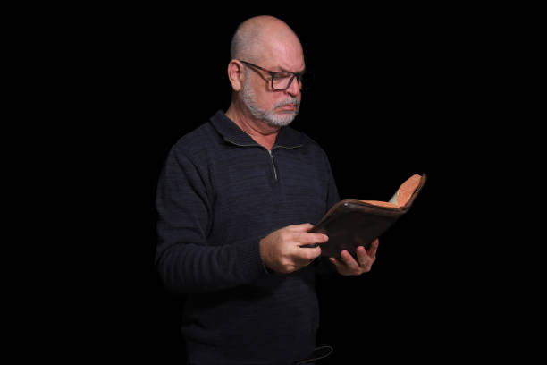 istock portrait of older man with beard doing reading isolated on black background 1481718158