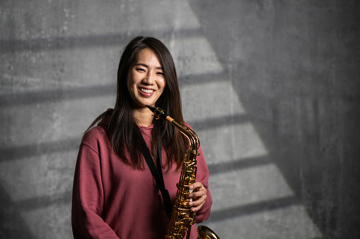 Portrait of a beautiful Japanese female saxophonist in studio.