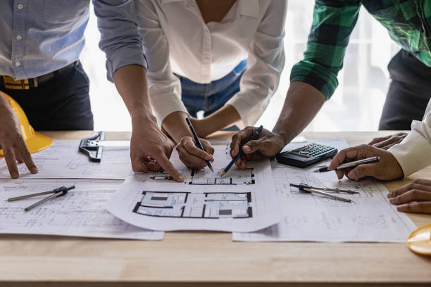istock Engineer pointing at blueprint and using laptop to draw project design building construction architect Contractor and foreman meeting with floor plan for real estate development project industry 1481720178