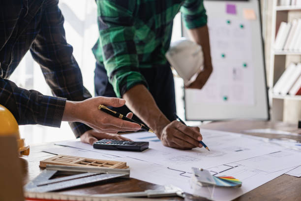 istock Engineer pointing at blueprint and using laptop to draw project design building construction architect Contractor and foreman meeting with floor plan for real estate development project industry 1481721291