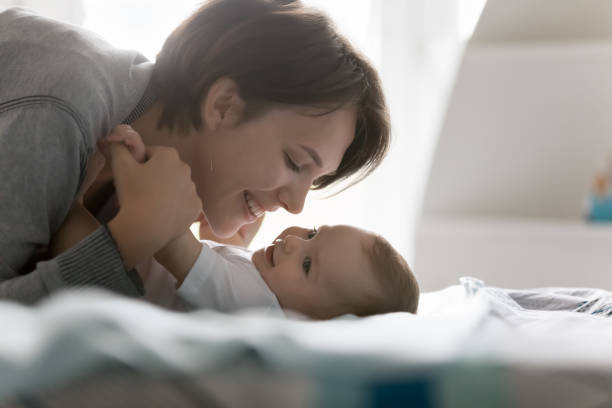 istock Happy cheerful new mom caressing adorable baby lying on back 1481721774