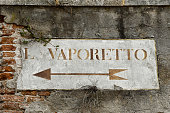 Close-up of an old stone directional sign to the vaporetto on a brick wall in a Venetian alley, Venice, Veneto, Italy