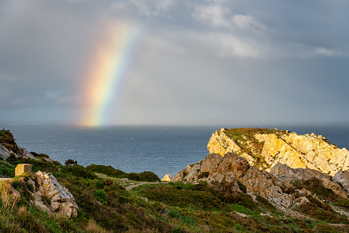 Rainbow formed by storms on the horizon of the sea seen from the cliffs of the shore, Asturias, Spain