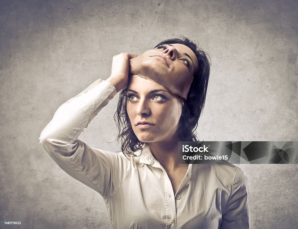 Hypocrisy Young woman putting off a mask of herself Two Faced Stock Photo