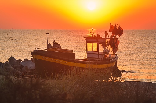 Beautiful boat on the beach with the rising sun. Photo taken in Gdynia, Poland.