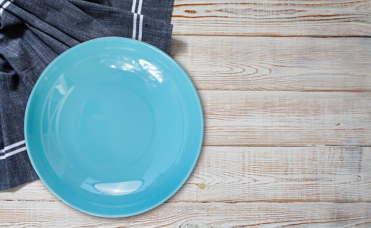 Empty blue plate and tablecloth on wooden table, flat lay top